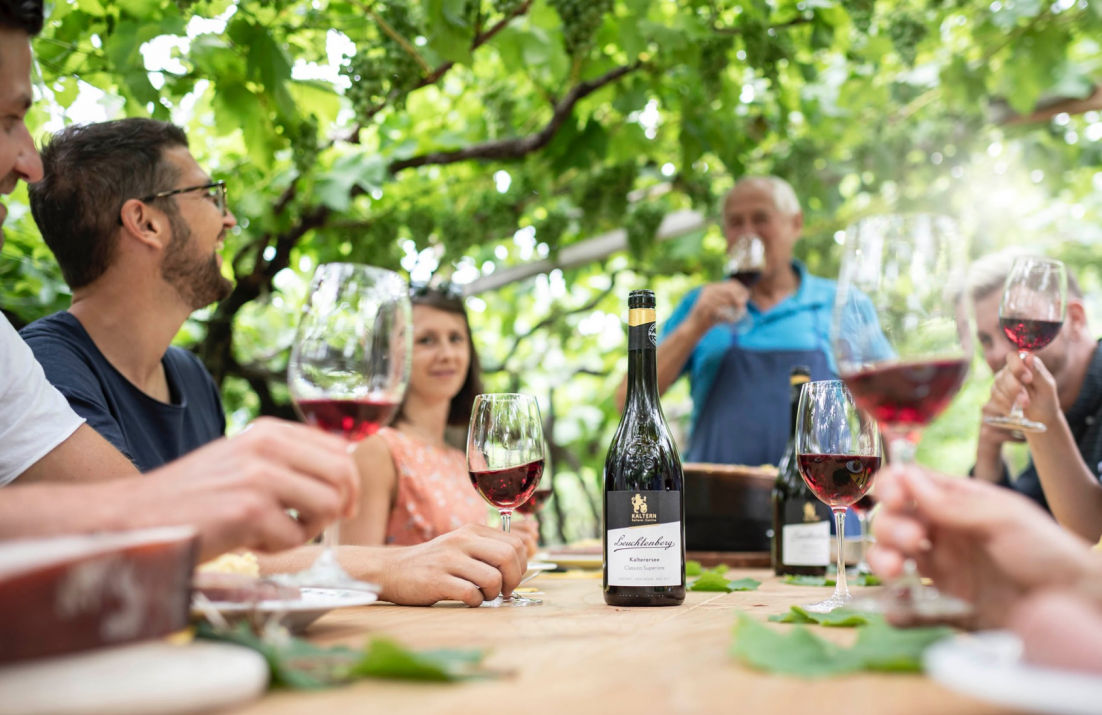 People drinking red wine round a table