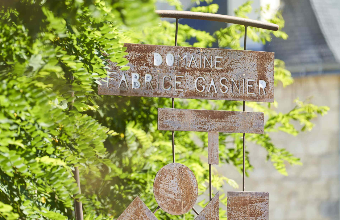 Rustic sign "Domaine Fabrice Gasnier" against greenery