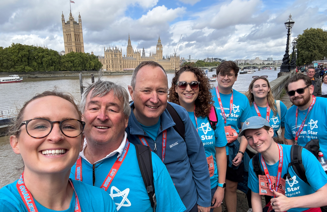 Ellis team wearing blue sponsored t-shirts beside Houses of Parliament on the Thames