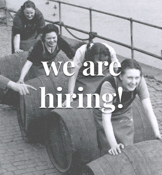 Historic black and white picture of women pushing wine barrels
