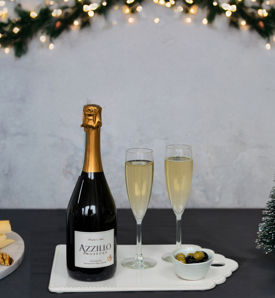 Bottle of Azillo Prosecco with flutes and decorative Christmas trees