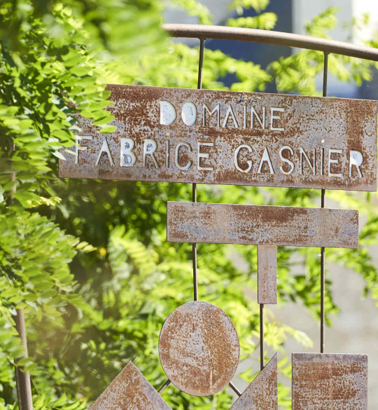 Rustic sign "Domaine Fabrice Gasnier" against greenery