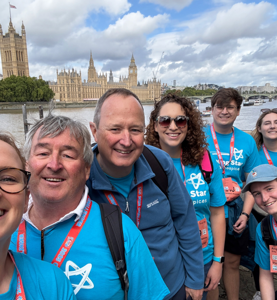Ellis team wearing blue sponsored t-shirts beside Houses of Parliament on the Thames